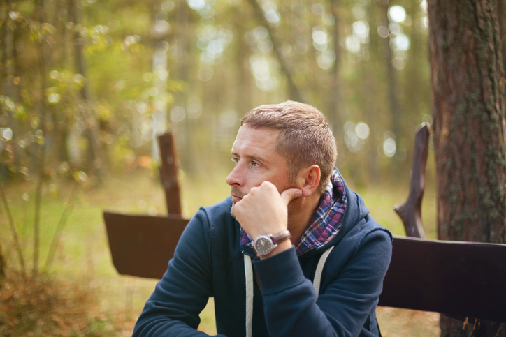 man thinking moody portrait, sitting at autumn park