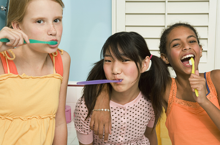 Three young girls practicing good oral hygiene.